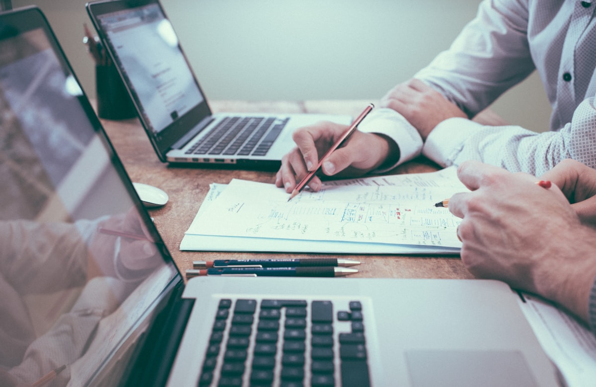Two colleagues reviewing attendance and payroll paperwork at a desk