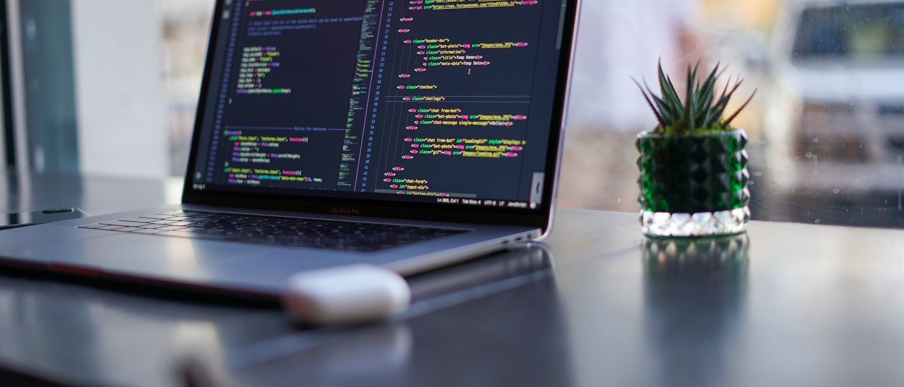 A laptop on a desk showing application source code mid-build